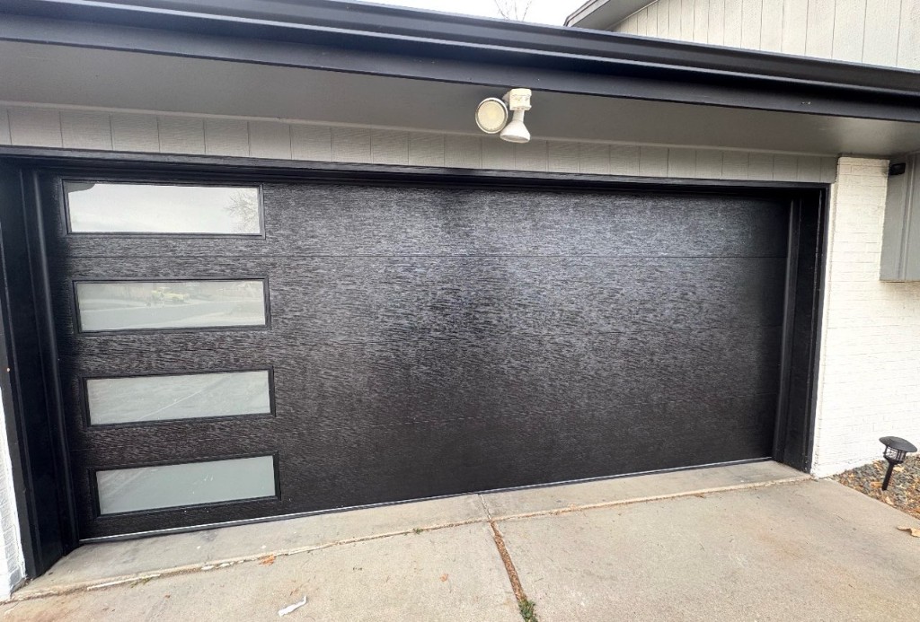 New black modern garage door with side windows after replacement